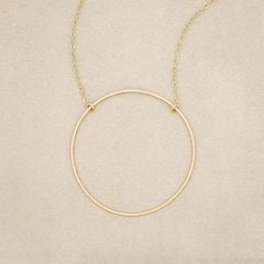 A gold filled It All Matters Circle Necklace, on beige background
