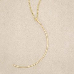 A gold filled New Moon Necklace, on beige background