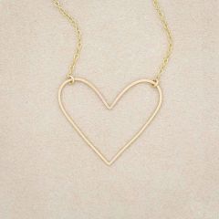 A gold filled Petite Peaceful Heart Necklace on beige background