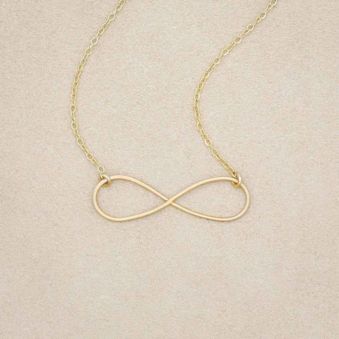 A gold filled Forever, For Always Infinity Necklace, on a beige background