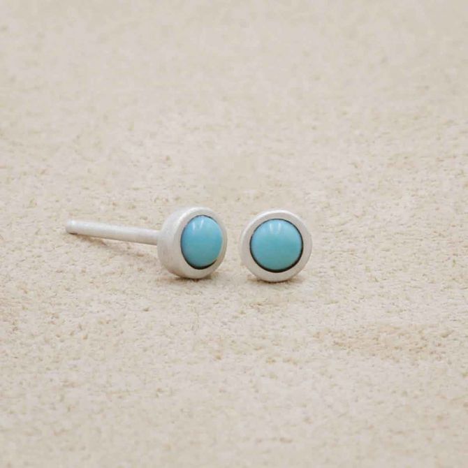 sterling silver Lighthearted Turquoise Stud Earrings on beige background