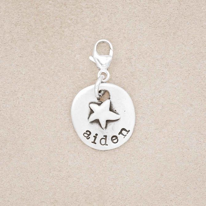 A personalized sterling silver Starry Disc Bracelet Charm on suede