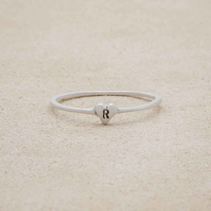 sterling silver Sweet Love Initial Ring - One Heart, personalized with an initial, on a beige background