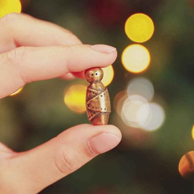 hand holding a gold plated baby jesus nativity figurine