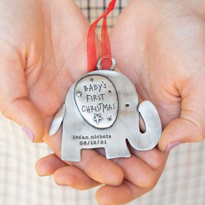 hand holding a baby's first Christmas ornament of an elephant hand-molded and cast in fine pewter. personalized with up to two lines with a name, phrase or date being hung on a Christmas tree