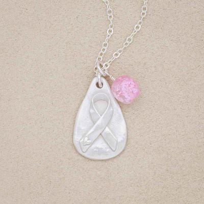 Breast cancer awareness necklace handcrafted in sterling silver with a matte brushed finish and hung next to a rose quartz bead