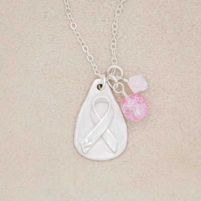 Cancer awareness necklace handcrafted in sterling silver with a matte brushed finish and hung next to a rose quartz and crystal bead