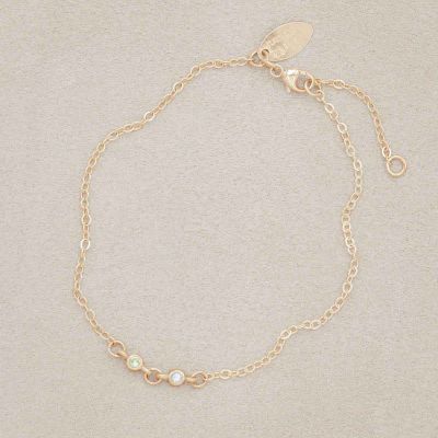 14k yellow gold Dainty Finespun Birthstone Bracelet - Small, personalized with 2mm birthstones on a beige background