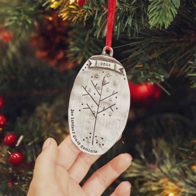 hand holding a personalized pewter Family Tree ornament that is hanging on a Christmas tree