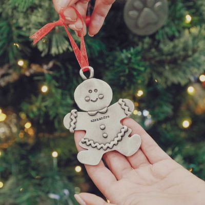 Gingerbread mom ornament hand-molded and cast in pewter with a personalized name being hung on a Christmas tree