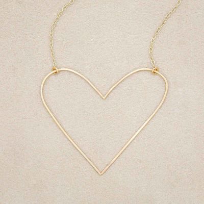 A gold filled Large Peaceful Heart Necklace, on beige background