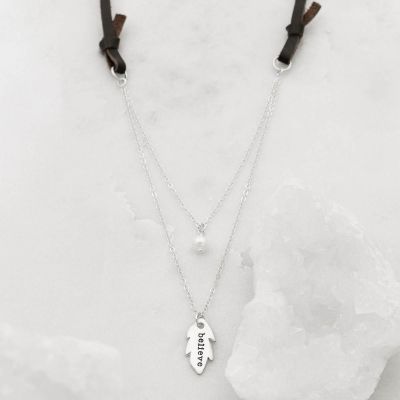 Limited edition found feather necklace handcrafted in sterling silver with the pendant hung next to a vintage freshwater pearl on a leather cord 