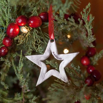 Molded star ornament hand-molded and cast in fine pewter hung from a sheer red ribbon and personalized with a up to five words placed on Christmas tree