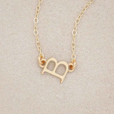 14k yellow gold my monogram letter necklace on beige background