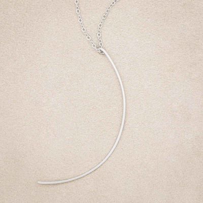 A sterling silver New Moon Necklace, on beige background