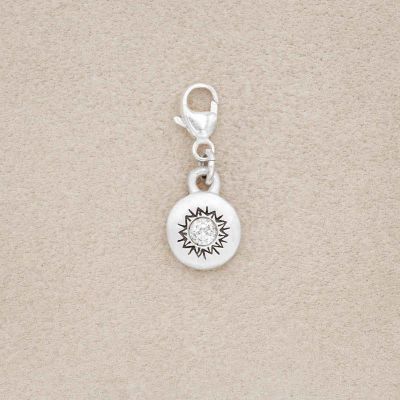sterling silver Sunburst Bracelet Charm with a 3mm cubic zirconia, on a beige background