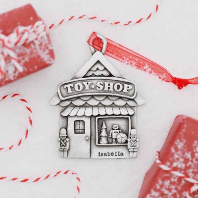 Toy Shop Ornament cast in pewter, surrounded by fake snow and gift boxes