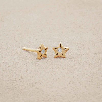 Your Spark Earrings, handcrafted in 14k yellow gold, set with a 1.5mm cubic zirconia, on beige background